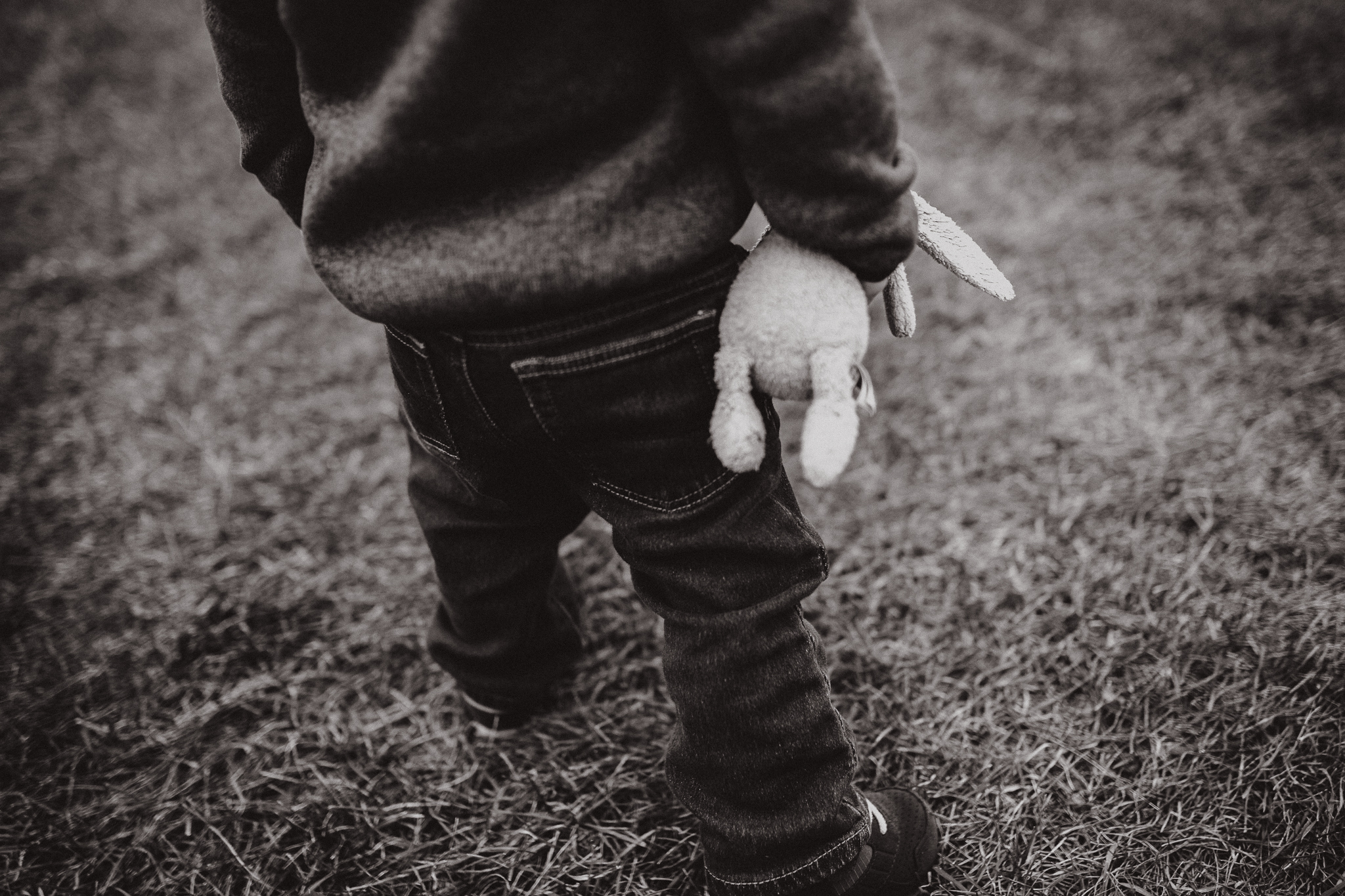 Toddler boy outside clutching his stuffed bunny.